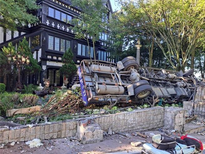 满载高丽菜的大货车撞倒民宿老英格兰的围墙后侧翻，驾驶受困在驾驶座。（民眾提供／杨静茹南投传真）