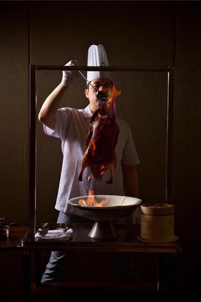 「潮萃火焰瀨尿燒鵝」以白蘭地燒灼澆淋燒鵝，桌邊開腹片鵝的噴香「食境」秀，非常吸睛。（神旺潮品集．潮坊提供）