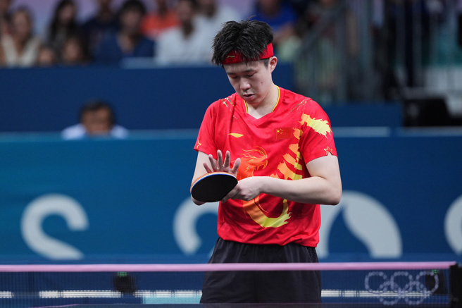 巴黎奥运会乒乓球男子单打32强赛，大陆队选手王楚钦2比4负于瑞典队选手莫雷加德，爆冷出局。图为王楚钦擦拭球拍。（图／中新社）