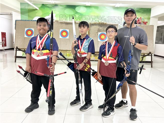 新手教練黃冠中（右一）帶領建國國小射箭隊參加青少年射箭公開賽，當中陳祈恩、林宸竹、盧建辰（左一至三）在U15男生組團體對抗賽的銅牌戰中，在滿分30分的賽制下以29分奪牌。（謝佳潾攝）