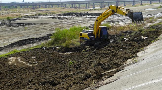挖土機挖土覆蓋堤防前坡基腳，再加上灌漿，雙重強固河堤。（寶智華攝）