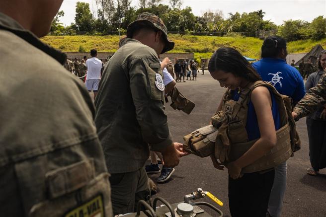 美军协助当地民眾试穿个人防护装备，实际感受装备重量。（取自DVIDS网站）
