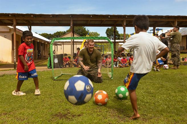 陆战队官兵与孩童同乐，一起踢球、挥洒汗水。（取自DVIDS网站）