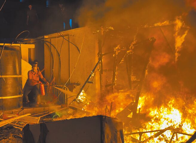 以色列4日对迦萨走廊中部发动攻击，引发大火，附近有巴勒斯坦难民营，巴勒斯坦人急着灭火。（路透）