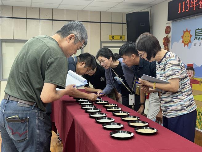 為鼓勵農友精進栽培技術並互相交流，台中市烏日區農會6日舉辦稻米競賽，評審委員現場細細查看稻米作品。（潘虹恩攝）