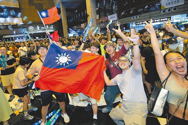 中華隊「麟洋配」王齊麟、李洋4日在巴黎奧運男子羽球雙打奪金牌，頒獎典禮上的國旗歌也感動台灣人。圖為民眾當晚在台北車站大廳的應援直播現場開心揮舞國旗。（本報資料照片）