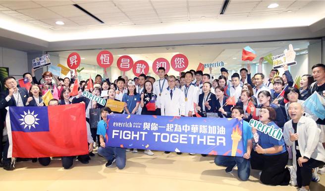 巴黎奧運射箭、羽球及射擊代表隊7日返台，機場免稅店人員高舉國旗歡迎選手。（范揚光攝）