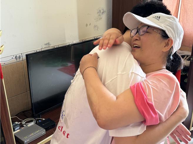 从小看着胡姓钓客长大的邻居阿姨(右)与他相拥而泣，欢迎他平安回家。(于家麒摄)