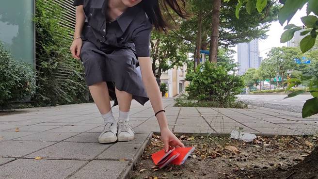 家属会将未婚亡者的生辰八字、地址放在红包后，丢在路边给有缘人捡。(游定刚拍摄)