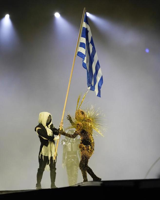 巴黎奧運閉幕式，蒙面人將希臘國旗交給黃金領航員。(美聯社)