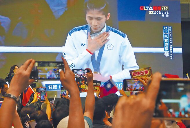 外媒称林郁婷用实力与毅力获得金牌，并粉碎外界不实的指控。图为林郁婷夺金，萤幕前的民眾拿着手机拍下歷史性的一刻。（赵双杰摄）