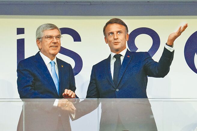 法国总统马克宏（右）和国际奥会主席巴赫于11日在奥运会闭幕式上握手。（美联社）