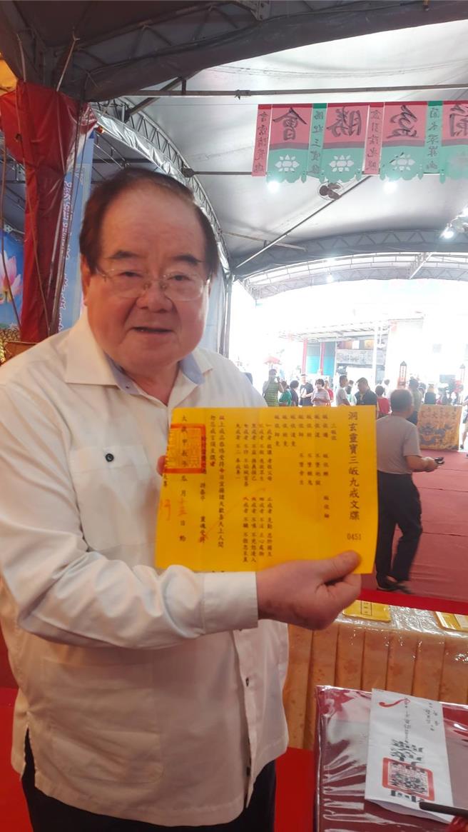 先啬宫董事长李乾龙（如图）手持三皈九戒文牒，表示法会后将牌位与文牒莲花灯法船一起焚化。（张铠乙摄）