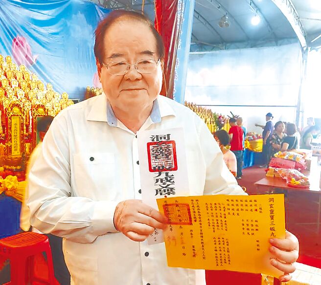 先嗇宮董事長李乾龍手持3皈9戒文牒，表示法會後將牌位與文牒蓮花燈法船一起焚化。（張鎧乙攝）