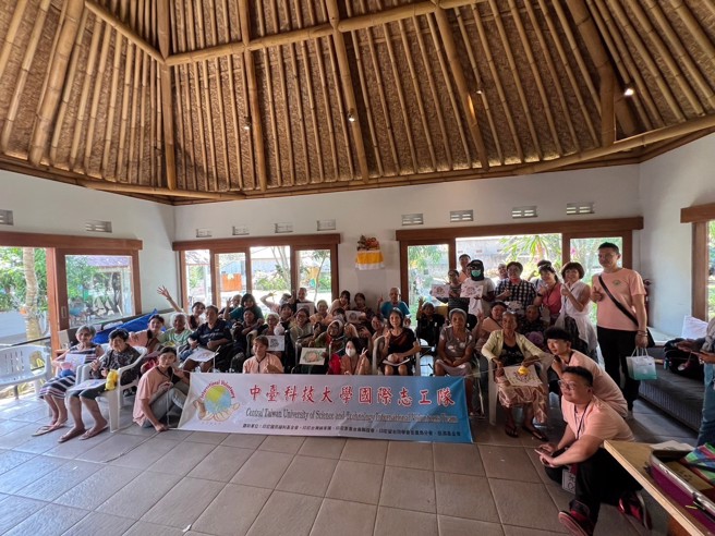 Panti Jompo Syailendra老人院和長輩們拿著藝術治療作品與志工隊合影。(照片/中臺科技大學提供)
