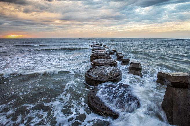 新豐鄉鳳坑漁灣有著名的「紅豆餅」防波堤，在漲潮時搭配落日夕陽，美不勝收。（羅浚濱攝）