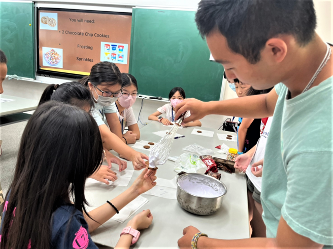 僑英青年大使(右)帶領光榮國小學生手作餅乾三明治。(照片/新北市政府教育局提供)
