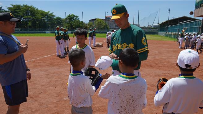 合庫隊投手吳昇峰為夏令營學童們簽名。（寶智華攝）