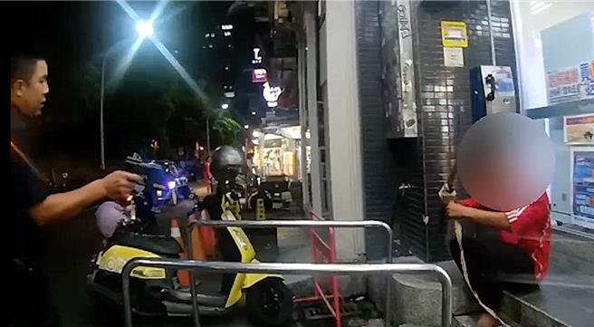 许男23日晚间酒后右手缠绕两把刀械独坐台中一中商圈1超商前，警方获报到场即拿出电击枪喝斥许男放下刀械。（民眾提供／冯惠宜台中传真）