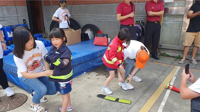 桃园市山脚消防分队今与直佑营造公司联合举办消防宣导夏令营活动，120位亲子共襄盛举，不但和搜救犬同乐、也体验消防负重亲子竞赛、横渡斜降、灭火器暨射水等。(蔡依珍摄)