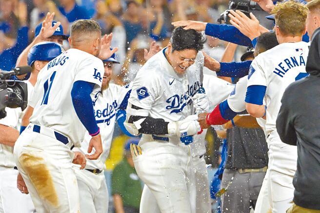 大谷翔平（中）轟出再見滿貫全壘打後，回到本壘被隊友包圍潑水慶祝。（路透）