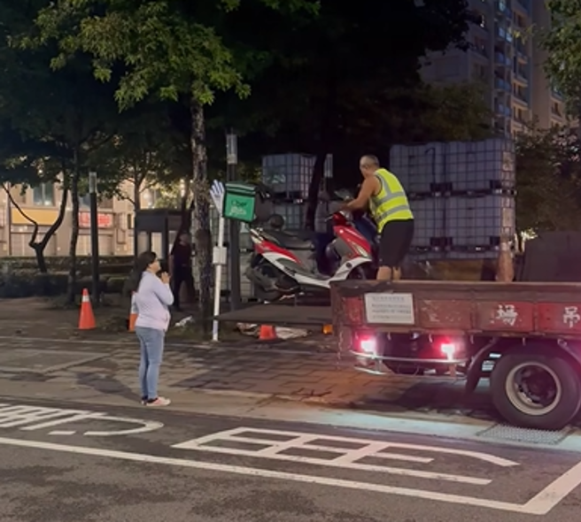 有民眾在网路上传影片，内容显示板桥合宜住宅社区外停靠着一辆拖吊车，相关人员正将违停的机车搬移上货车后斗。（图 / 翻摄自脸书社团「外送甘苦谈」）