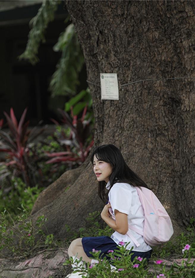 李多慧与彰化县永靖乡永北村大发路上的茄苳树合影，穿着附中制服的她坐在树下，俏皮模仿台东金城武树的场景。（成美文化园提供／孙英哲彰化传真）