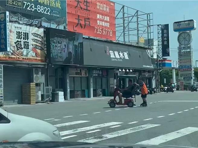 彰化市金馬路與永安街口今天上演離譜場景，1名老先生騎乘電動代步車時，後方竟附掛著1名穿著直排輪的國中生。（民眾提供／孫英哲彰化傳真）