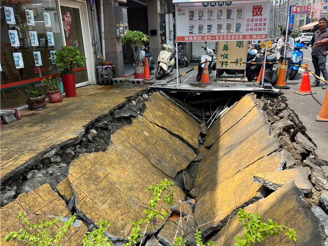 云林县斗六市文化路1家房屋仲介门口路面，31日突然「轰」一声塌陷，出现长约7公尺、宽4公尺、深1.5公尺的「天坑」，幸好当时无人行经，不过有2辆机车掉落坑内受损。（张朝欣摄）