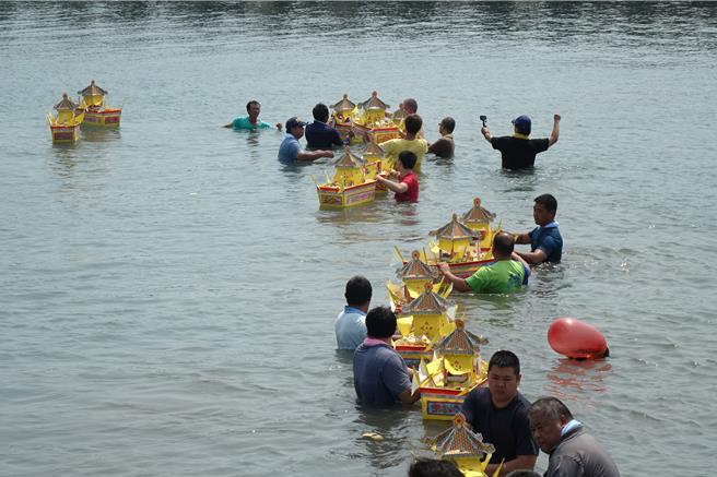 东港东隆宫在镇海公园施放东港特有的船型水灯，船型水灯一一点燃送入海中。（罗琦文摄）
