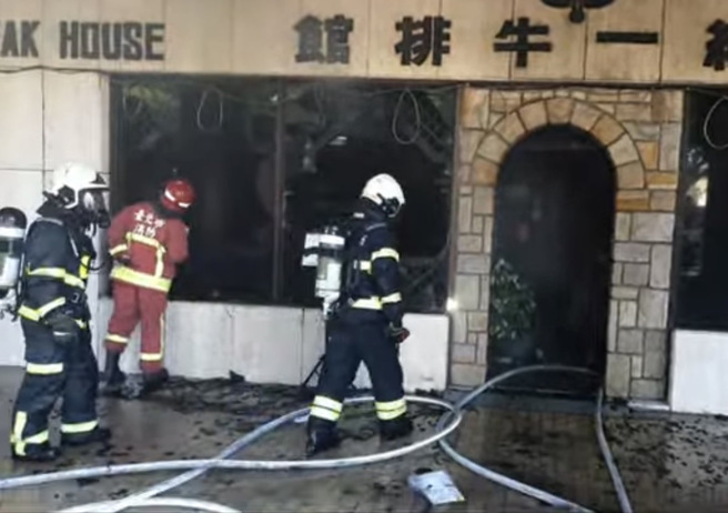 松山「小统一牛排馆」火警 ，警消到场后立刻破窗射水灌救。(戴志扬翻摄)