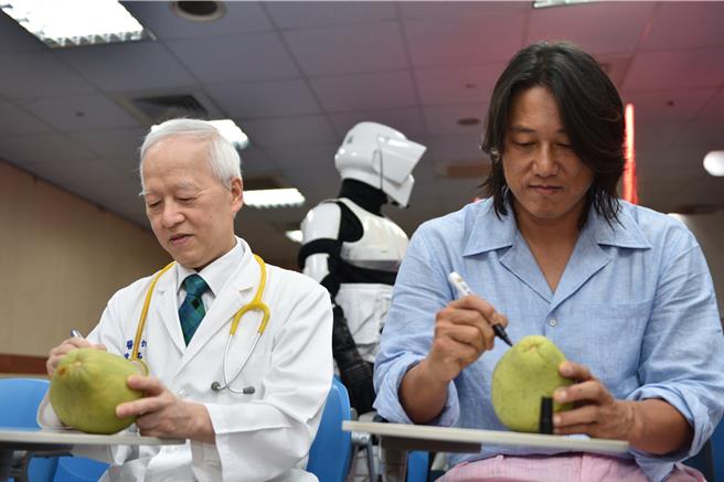 马偕儿童医院院陈铭仁（左起）和韩哥一起手绘文旦。（马偕医院提供）