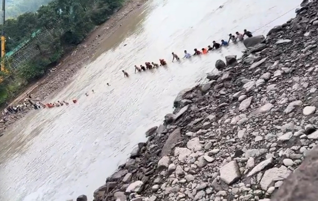 上百亲友搭起人桥，拦河搜救落水失踪的小英莫。（图／摄自 微博）