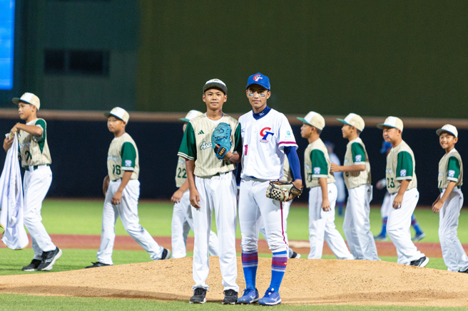 龟山国小少棒队7日来到天母棒球场为U18亚青开球，赖承希（左）开球后与接球捕手黄天赐（右）合影。（台湾世界少棒联盟提供）