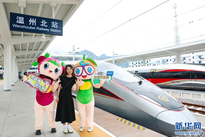 杭溫高鐵首批乘客在始發站台與列車合影。（新華社）