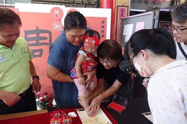 万峦抓周迎新丁新枝，小宝宝穿着虎衣虎帽盖脚印。（罗琦文摄）