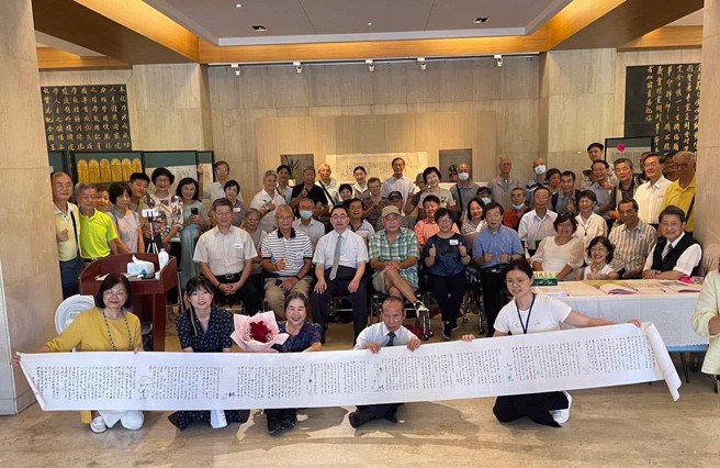 2024/9/9 政大毛笔情书展的与会贵宾在4.5公尺长的情书背后大合照。(周祝瑛教授提供)