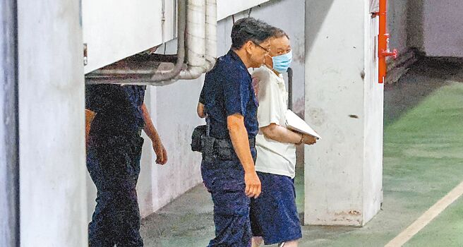 检察官9日提讯沈庆京（白衣者），只见他虚弱的坐在轮椅上，被法警押解进地检署，经讯后3小时，在法警戒护下，用走的出来搭囚车离去。（邓博仁摄）