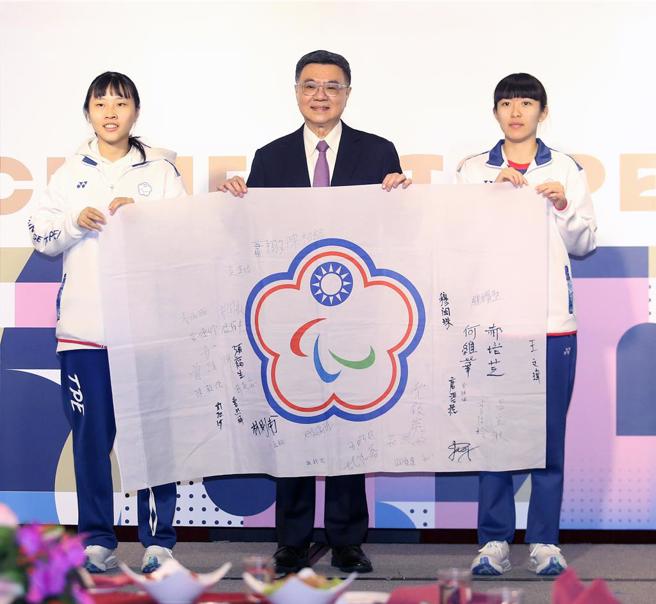 行政院长卓荣泰（中）11日出席2024巴黎帕运会代表团返国餐会，桌球选手田晓雯（左）及林姿妤（右）致赠签名会旗作为纪念。（范扬光摄）