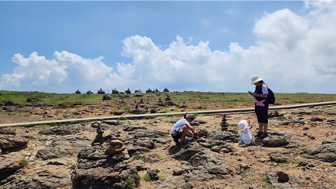 探索澎湖獨特地形地貌和秋季人文景觀，澎管處13日推「秋之奇岩季」踩線團，圖為小門鯨魚洞附近，遊客自動玩起疊石。（許逸民攝）