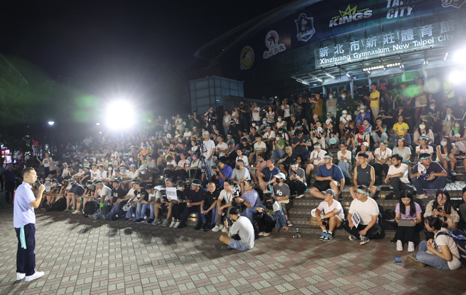 民眾党「Justice！为司法公义站出来」新北场宣讲活动13日在新庄体育馆外举行，支持者坐在体育馆前的台阶上聆听台上演讲。（资料照片/姚志平摄）