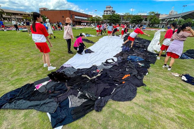 冬山國中250名師生14日在學校操場中，以二手衣物拼接成鯨魚等海洋生物。（李忠一攝）