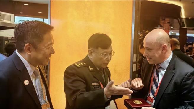 何雷（中）向美方代表团团长、美国国防部副助理国防部长蔡斯（右）赠送中国人民解放军军事科学院的徽章。（北京日报）