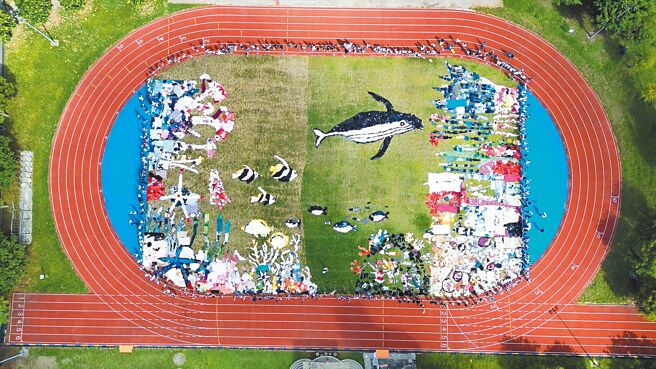 宜兰县冬山国中与艺术家吴成夫合作，14日用二手衣拼接，完成大型地景作品「鲸天动地」。（冬山国中提供／李忠一宜兰传真）