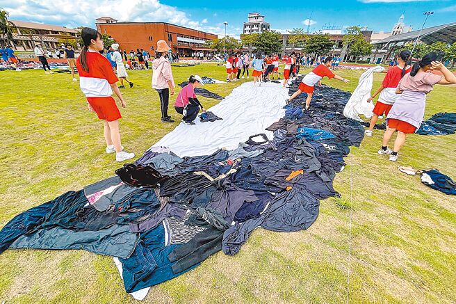 宜兰县冬山国中250名师生14日在学校操场中，以二手衣物拼接成鲸鱼等海洋生物。（李忠一摄）