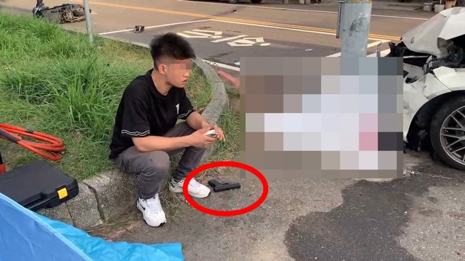 車禍現場駕駛呆坐路旁，婦人被當場撞死，駕駛腳邊還有一把道具槍。（翻攝畫面）