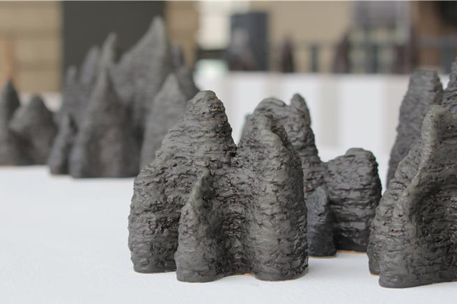 陶艺家邱永丰介绍，作品黑色外观是由妈祖庙香灰氧化成色而成。（贺培晏摄）