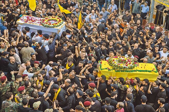 接連發生呼叫器和對講機爆炸攻擊，重創真主黨，在貝魯特的送葬儀式中，哀悼者抬著遇難者的棺材。（美聯社）