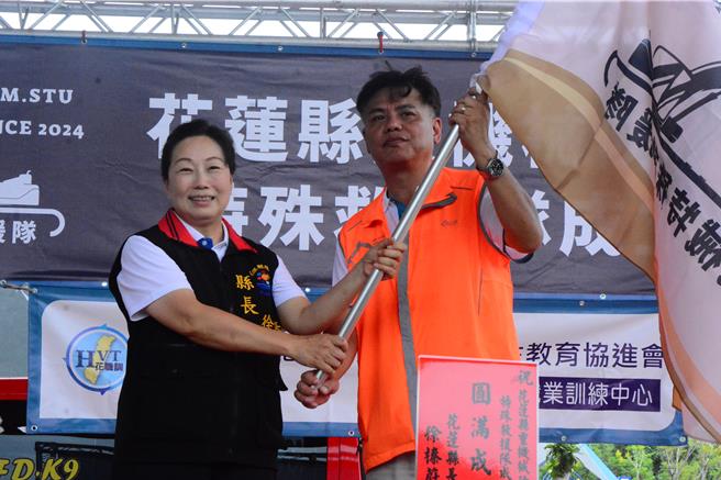 花莲县重机械防灾协会今于消防训练大楼举办特殊救援队成立大会，县长徐榛蔚（左）授旗理事长张铭伟（右）。（王志伟摄）