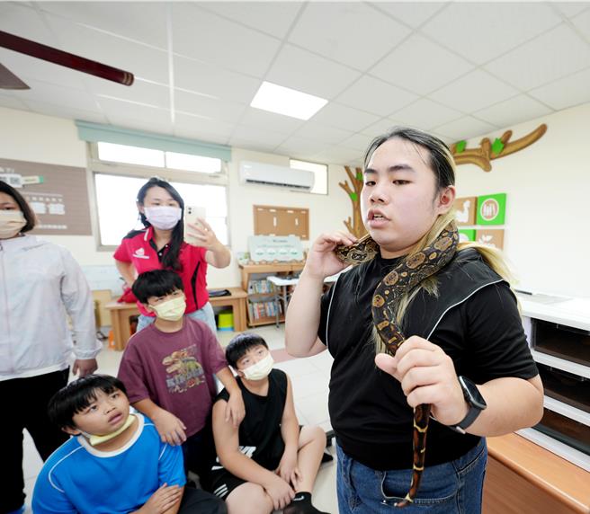 林建廷与原色红尾蚺互动，带小朋友认识爬虫类的生态环境。（中华圣母基金会提供／廖素慧嘉市传真）